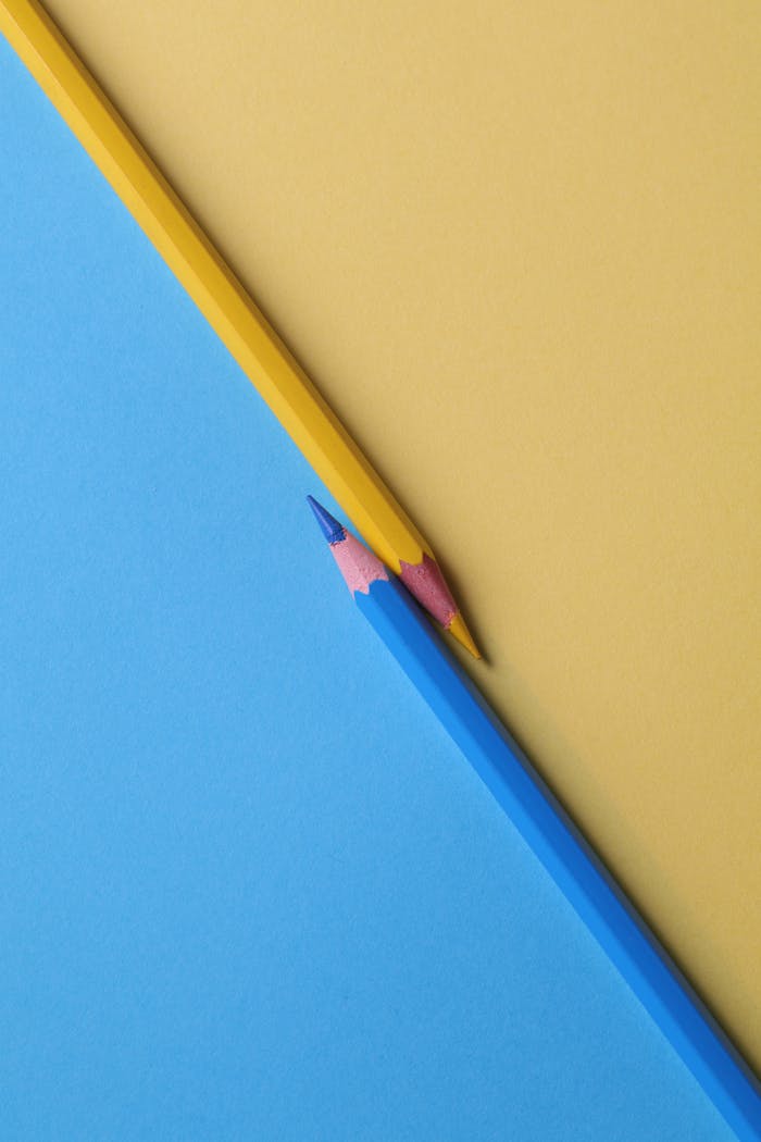 who-we-are Close-up of vibrant yellow and blue colored pencils on contrasting paper backgrounds.